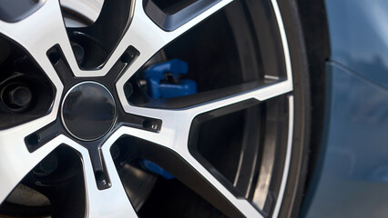 Car detailing closeup alloy wheel with tires and blue calipers side view 16x9 shot.