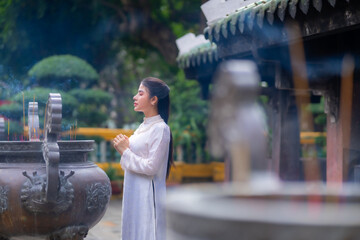 Vietnamese girl with Ao Dai dress standing in temple in Ho Chi Minh city, Vietnam. Ao dai is famous...