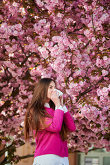 Woman allergic suffering from seasonal allergy at spring in blossoming garden at springtime. Woman...