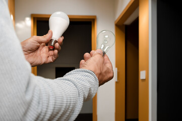 Man holding energy saving led lamp and refusing incandescent light bulb. Comparison of incandescent...