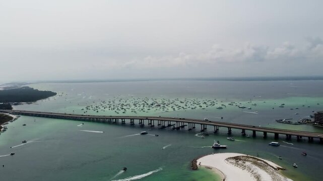 view of William T. Marler Bridge with Crab Island, Destin Florida in background crowded with boats, and norriego point in foreground