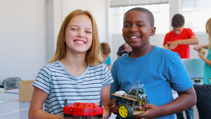 Portrait Of Male And Female Students Holding Robot Vehicle In After School Computer Coding Class 