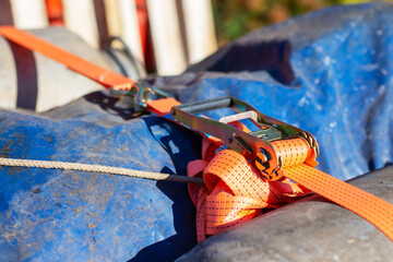 This is a detailed closeup shot of a ratchet strap connected to a blue tarp