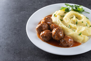 Meatballs with mashed potatoes on black slate background. Copy space