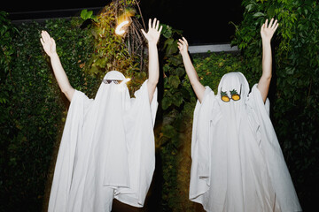 Happy couple wearing ghost costumes and dancing at Halloween party