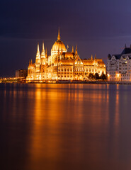 Obraz premium Budapest, Hungary - September 17, 2024: Budapest Parliament Reflecting Over Danube in the Night. Night long exposure shot.