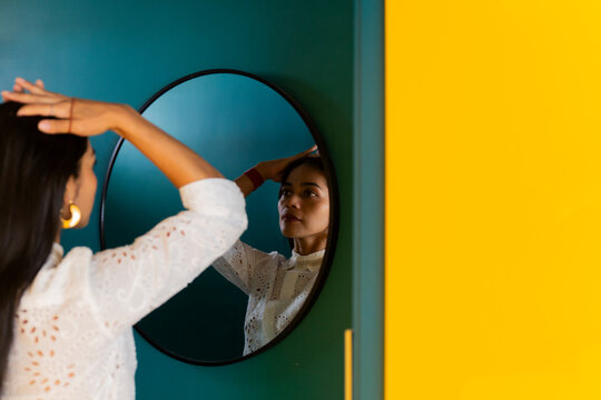 Woman doing hairstyle and looking in mirror