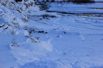 A snow covered mountain with bushes and a river in the background