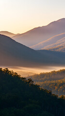 Obraz premium Majestic mountain range at sunrise with low-hanging mist gently rolling through the valleys
