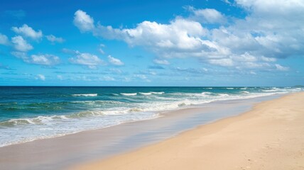 Scenic beach view with golden sand, gentle waves, and clear blue sky.