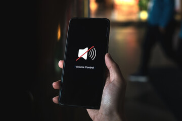 Hand pressing volume of the smartphone in silent or mute mode activated.