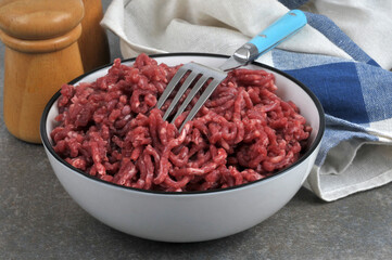 Viande de bœuf hachée crue dans une assiette avec une fourchette en gros plan