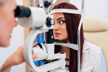 Beautiful female doctor ophthalmologist is checking the eye vision of senior woman in a modern clinic. Doctor and patient during medical check up in ophthalmology clinic.
