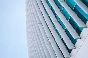 A close-up view of a stunning skyscraper, showcasing its architectural beauty against a backdrop of bright, fluffy clouds in a clear blue sky