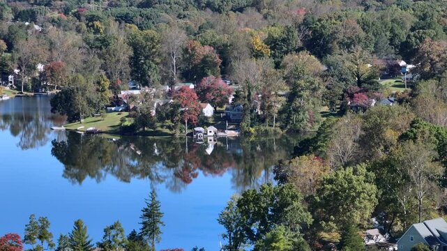 Natural tranquil lake with luxury villas and private access on Autumn n day. Aerial panning zoom shot. Timber Lake in Virginia during sunny day with colorful foliage trees.