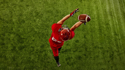 Top view image of concentrated man, American football player in red uniform in motion on stadium, catching ball with precision. Concept of sport, competition, tournament, game. Copy space