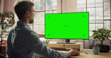 Professional Black Female Using Green Screen Monitor for Content Creation. Creative working on Chroma Key Display. Modern Home Office with Minimalist Interior. Over the Shoulder Shot 