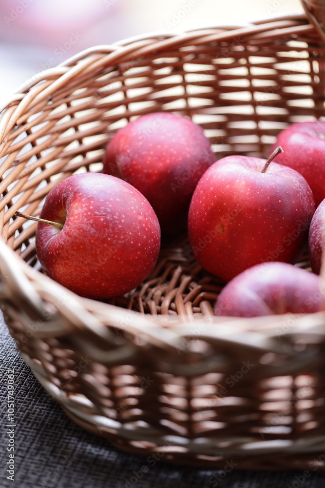 Poster fresh red apples stored in a woven wicker basket.