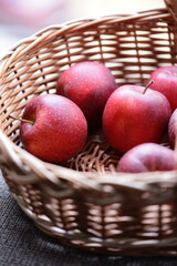 Fresh red apples stored in a woven wicker basket.