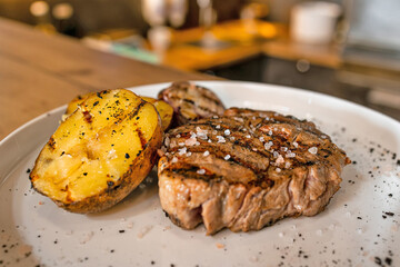 Juicy grilled steak with seasoned potatoes served on a white plate