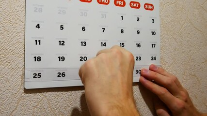 Male hands moving red frame cursor of a wall calendar to Thanksgivingdate 2024