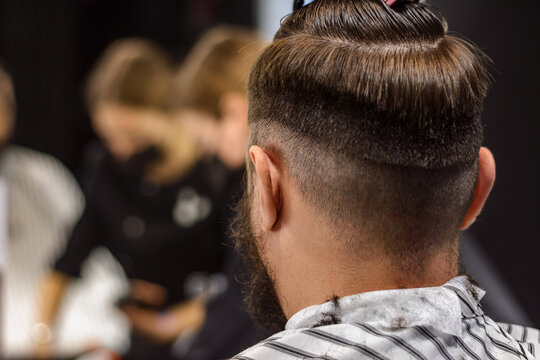 Back view, no face, selective man on haircut. Haircut stage. Step-by-step training of men's haircuts. Self-care. Hairdresser and client while shaving and trimming beard in classic barbershop