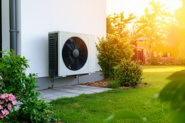 Modern air source heat pump on outside wall of suburban house. Sustainable energy solution for residential building. Home building with air conditioning unit