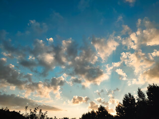 Vivid orange clouds over the forest at sunset. Colorful clouds on the dramatic sunset sky.