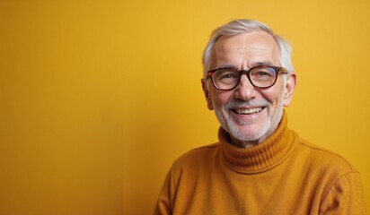 Obraz premium Cheerful senior man smiling brightly against vibrant yellow background with copy space