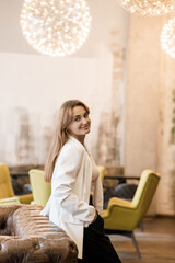 Obraz premium Elegant woman in stylish attire posing in a modern cafe setting with designer lighting