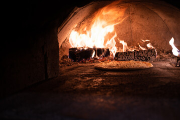Close-up of a margarita pizza baking in a hot wood fire oven