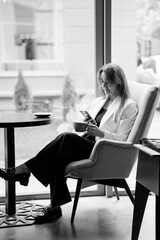 Elegant Woman in a Cafe Engrossed in Her Phone