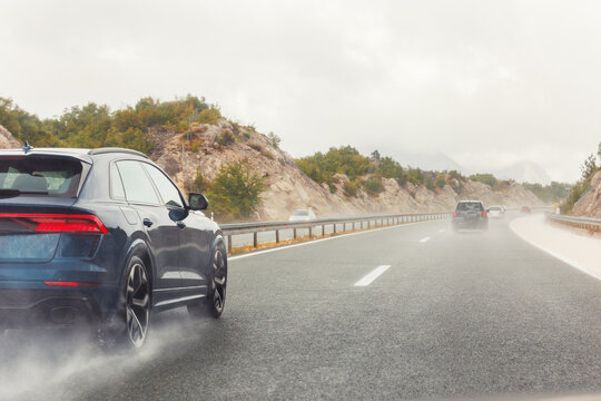 Back tail view of many cars driving fast on wet highway road after rain in Europe. Automobile accident vehicle rush hour collapse. Aquaplaning danger risk. Transportation vacation seasonal stuck