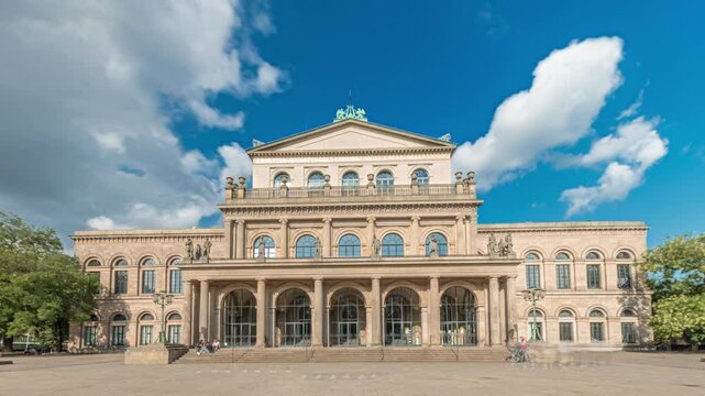 Hyperlapse of Hanover State Opera (Staatsoper Hannover) front view. A classical-style theater with people walking across the downtown square under a vibrant blue cloudy sky timelapse. Germany