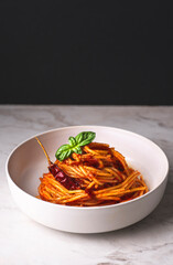 Spaghetti all'assassina is a typical Apulian recipe, Bari. Trendy first course, pasta cooked directly in a pan with tomato sauce, for a charred, crunchy and spicy flavor, front view, new Italian pasta
