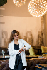 Elegant Woman Checking Time in Modern Restaurant with Ambient Lighting