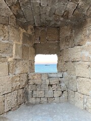 old castle window looking out on to an ocean sunset