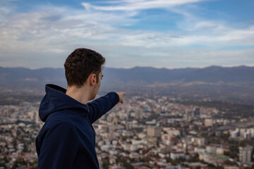 young man chooses his favorite building overlooking the city from the height of the mountain near the metropolis.