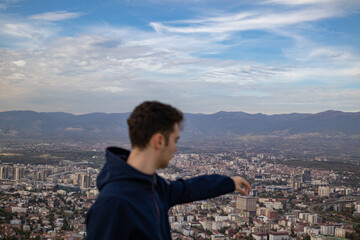 young man chooses his favorite building overlooking the city from the height of the mountain near the metropolis.