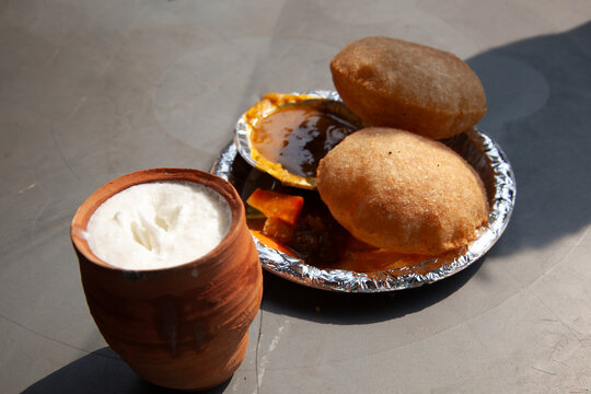 Traditional street food consisting of fried bread (puri) with aloo potatoes and a yogurt drink (lassi), Old Delhi, India