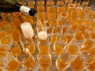 Full frame overhead view of prosecco being poured into glasses with peach puree to make bellini cocktails