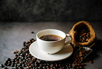 Americano coffee cup and roasted coffee beans falling in a burlap sackon gray background, Black coffee cup aromatic