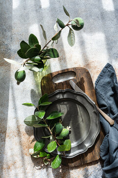 Overhead view of a rustic place setting with fresh feijoa fruits on a pewter plate and wooden chopping board