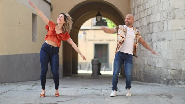 Dancers performing salsa steps in urban environment