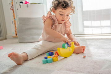 Vertical photograph of a girl playing with wooden balance toy. pieces, colors and different shapes to practice motor skills. Montessori education and materials. development and skills in childhood