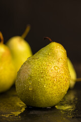 a green ripe pear covered with drops of water on the table
