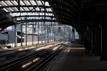 Infrastructure of railway tracks equipped with overhead electric poles in parallel to high powered supply lines in suburban.