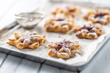 Sweet dessert pastries made of puff pastry with strawberry jam filled with caramelized apple sprinkled with powdered sugar