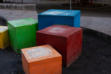 several cement boxes of different sizes, arranged in the shape of a staircase and colored with various colors.