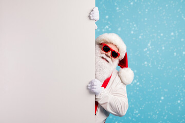 Naklejka premium Portrait of his he nice attractive funky cheerful white-haired Santa holding copy space placard announcement promotion isolated over bright vivid shine vibrant blue color background